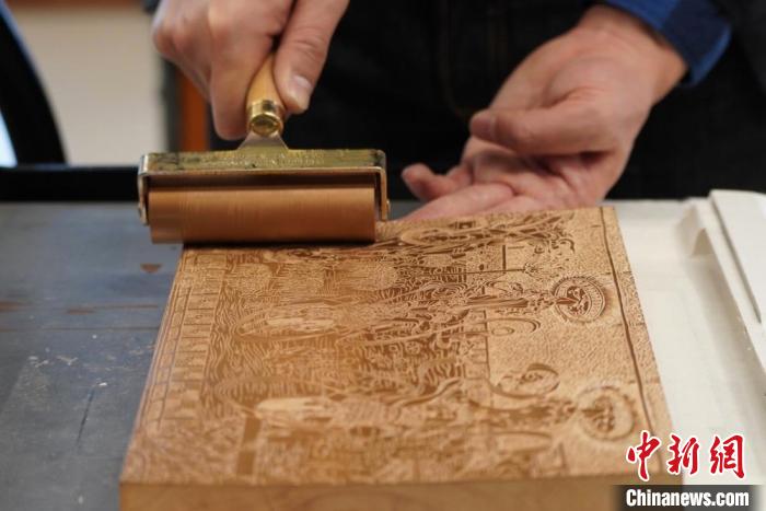 圖為徐晉林工作室工作人員正在給雕好壁畫的版面滾油墨?！【琶赖┰?　攝