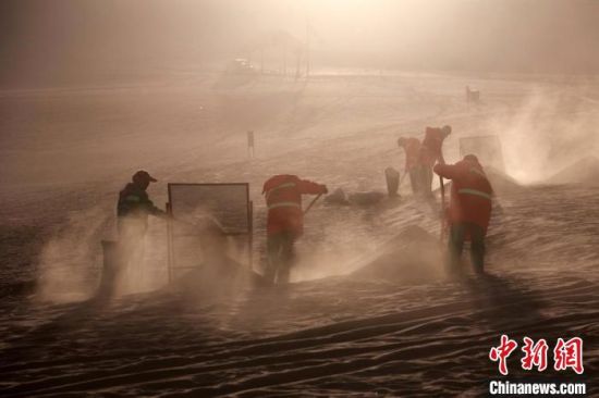 圖為敦煌市鳴沙山月牙泉景區(qū)“駱駝保姆”清理駱駝糞便?！垥粤?攝