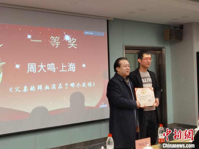 圖為作家、西北師范大學(xué)新聞與傳媒學(xué)院院長徐兆壽頒發(fā)一等獎證書，代領(lǐng)獎?wù)呱吓_領(lǐng)獎?！钅?攝