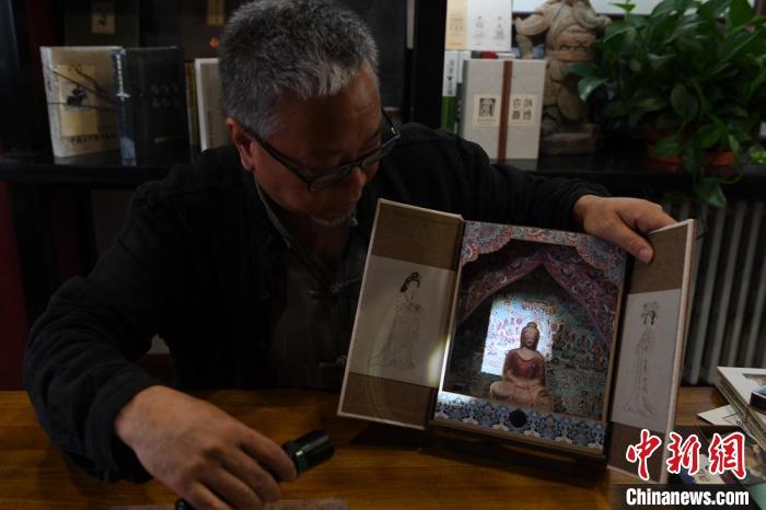 圖為讀者出版集團(tuán)讀者晉林工作室獨(dú)立出品人徐晉林，展示互動(dòng)性強(qiáng)的敦煌題材手工書。(資料圖) 楊艷敏 攝
