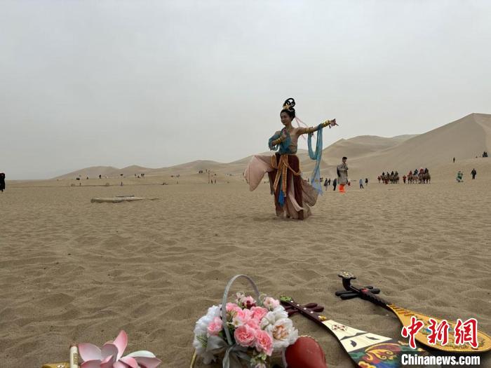 圖為2023年4月底，敦煌大漠“逐舞者”奧楠在鳴沙山月牙泉景區(qū)視頻直播敦煌舞?！●T志軍 攝