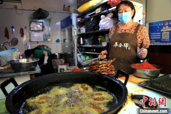 圖為平安驛·河湟民俗文化體驗(yàn)地內(nèi)的商戶炸干板魚?！⊙Φ?攝